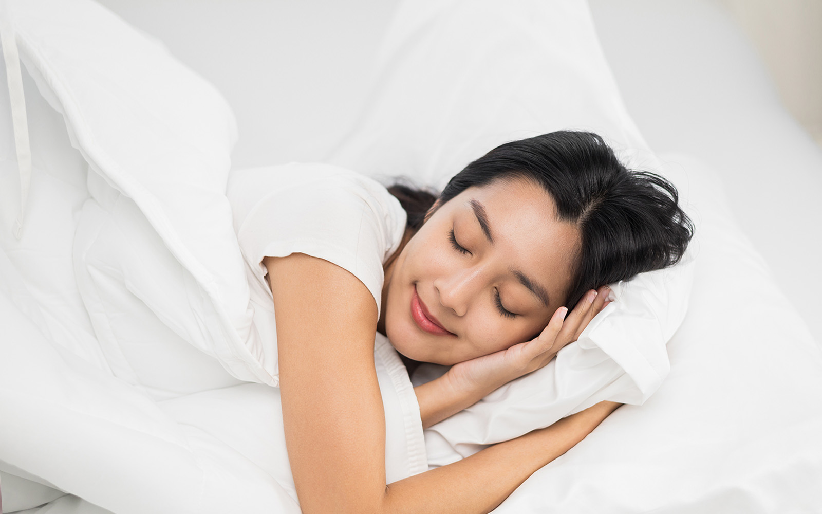 The image depicts a person lying in bed with their head resting on a pillow, appearing to be asleep or resting.