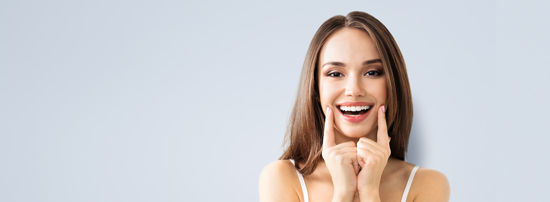 The image features a young woman with light skin, smiling and holding her hand to her chin. She is looking directly at the camera.